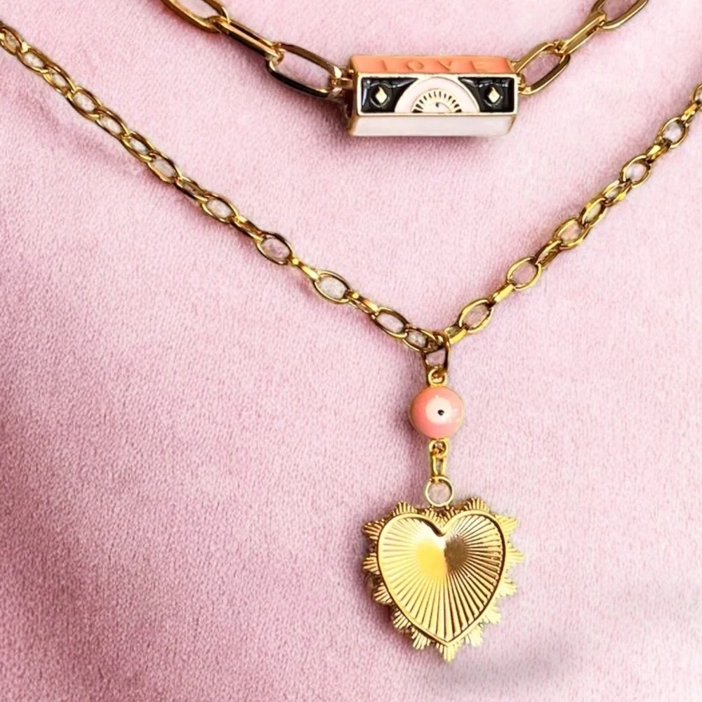 Gold toned chains with black, white, gold, and pastel pink enamel charms.
